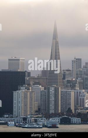 Vista diurna sfocata dello skyline di San Francisco con la Piramide Transamerica, edifici densi del centro città e un lungomare tranquillo con barche sotto un o Foto Stock