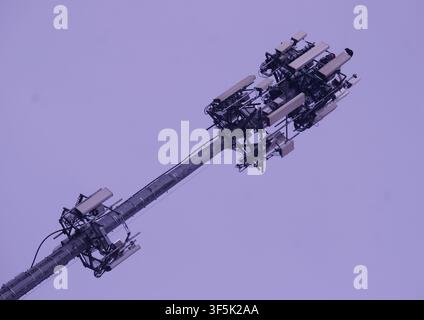 Prima piano ad angolazione bassa di una moderna torre di comunicazione cellulare con più antenne contro un cielo nuvoloso. Per concetti di 5G, telecomunicazioni Foto Stock