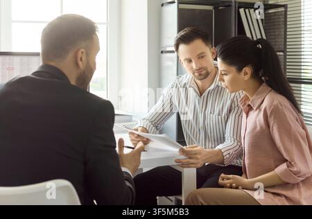 Coppia che esamina documenti con un agente immobiliare su contratto e mutuo Foto Stock