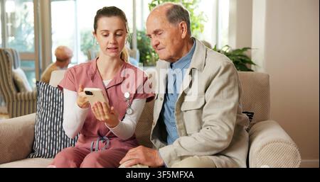 Anziano, uomo e infermiera con telefono in una casa di riposo per l'assistenza sanitaria online, consulenza o aiuto web. Donna, badante o persona maschile sul divano con smartphone Foto Stock