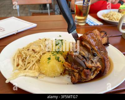 ABB/GARMISCH- Porzione di menu di cotenna di maiale arrostita con gnocchi e insalata di cavolo coltello posate su un piatto di porcellana servito su un tavolo di legno all'Elchs Almhuette la Windbeutelalm. Il rifugio di montagna si trova sopra Garmisch direttamente sul Kramerplateau sentiero escursionistico Bavaria Germania *** ABB GARMISCH Menu: Una porzione di cotenna di maiale arrostita con gnocchi e insalata di cavolo coltello e forchetta su un piatto di porcellana servito su un tavolo di legno alla Windbeutelalm, un rifugio di montagna nell'Elchs capanna alpina. Il rifugio di montagna si trova sopra Garmisch, direttamente sul Kramerplateau, su un sentiero escursionistico in Bavaria, Germania. Foto Stock