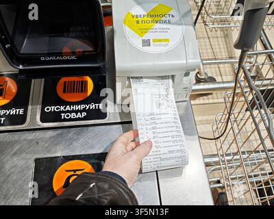 Kirov, Russia - 8 febbraio 2026: Cliente utilizza un terminale self-service nell'area della cassa del supermercato per scansionare gli articoli e stampare lo scontrino per l'acquisto Foto Stock