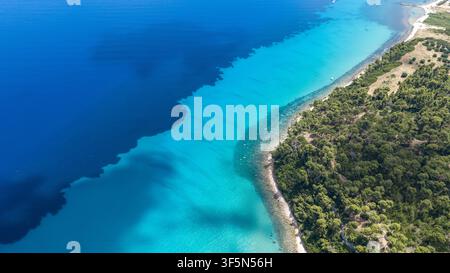 Questa immagine cattura le acque turchesi vibranti lungo la costa vicino a Kallithea in Grecia. La riva è delimitata da dense foreste verdi e una natu Foto Stock
