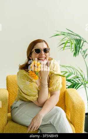 Donna gioiosa in camicetta gialla con girasoli Foto Stock