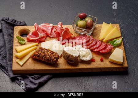 Formaggi assortiti e affettati su un tavolo di legno, piatto classico di antipasti per vino e riunioni Foto Stock