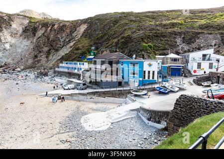 Scena costiera a St Agnes sulla costa della Cornovaglia, che mostra una piccola spiaggia circondata da scogliere rocciose ripide. Gli edifici si trovano alla base delle scogliere accanto Foto Stock