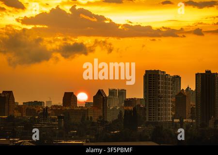 Kyiv, Ucraina: vista al tramonto sul quartiere residenziale di Novopecherski Lypky con alti palazzi residenziali, cielo dorato, nuvole drammatiche, industria Foto Stock