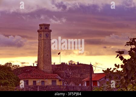 Torre dell'orologio della fortezza di Galle, Sri Lanka al tramonto con persone in piedi sul Bastione delle Stelle sullo sfondo Foto Stock