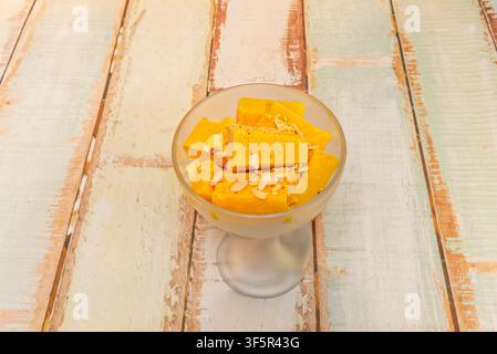 Dessert Kulfi al mango affettato guarnito con noci, servito in una coppa smerigliata Foto Stock