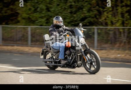 Milton Keynes, Regno Unito - 2 agosto 2026: Uomo in sella a una moto Harley-Davidson Street Bob del 2014 che guida su una strada britannica Foto Stock