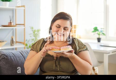 Dolce dessert di torta a ciambella gustoso da mangiare, donna obesa affamata e felice con grasso eccessivo che sorride Foto Stock