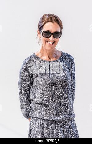 Victoria Hislop si trova davanti a uno sfondo chiaro. Sorride mentre indossa occhiali da sole e un abito a fantasia. La scena mostra una giornata luminosa e soleggiata Foto Stock