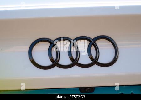 Prima del badge con logo a quattro anelli di Audi sul portellone bianco di un'auto con la telecamera di retromarcia visibile sotto Foto Stock