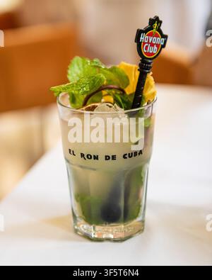 L'Avana, Cuba, 30 marzo 2022, Rinfrescante cocktail Mojito con menta fresca e lime su un tavolo durante l'estate in un bar a Cuba con un bastoncino per mescolare. Foto Stock