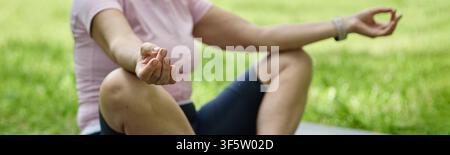 Donna di mezza età in meditazione nella posizione del loto su un tappeto da yoga nel parco Foto Stock