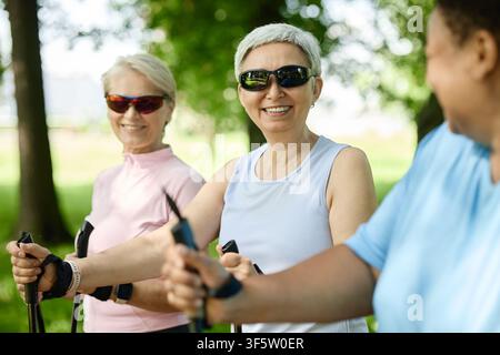 Ritratto di una donna anziana asiatica sorridente che fa Nordic Walking con amici nel parco Foto Stock