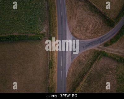 Un drone aereo cattura una vista dall'alto di un incrocio stradale rurale con campi su entrambi i lati a Lanreath, Regno Unito. Foto Stock