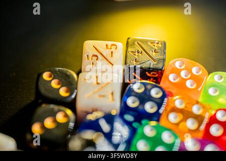 Pile di dadi traslucidi e vivaci a sei facce e gettoni di gioco specifici su una superficie scura Foto Stock