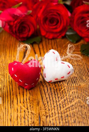 Due cuori con rose rosse sullo sfondo di legno Foto Stock
