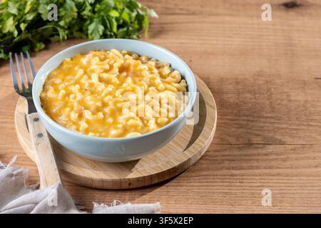 Mac e formaggio cremoso in una ciotola su un tavolo di legno Foto Stock