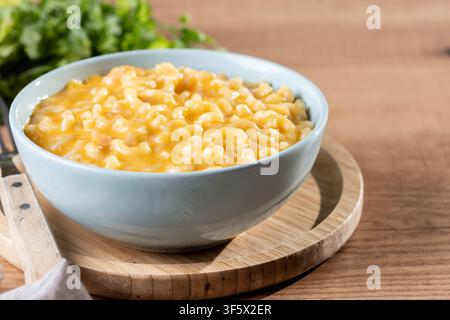 Mac e formaggio cremoso in una ciotola su un tavolo di legno Foto Stock