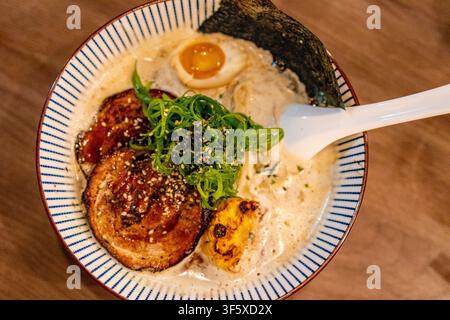 Vista dall'alto di una ciotola di ramen al miso cremoso con chashu di maiale, mais dolce e uovo ajitama. Concetto confortante di ramen giapponese per la cena al ristorante e il comfort Foto Stock