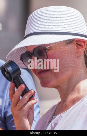 4 agosto 2026 Donna che tiene un ventaglio portatile manuale Foto Stock