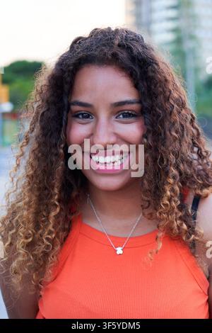 Giovane donna nera sorridente all'aperto in un ambiente urbano. Foto Stock