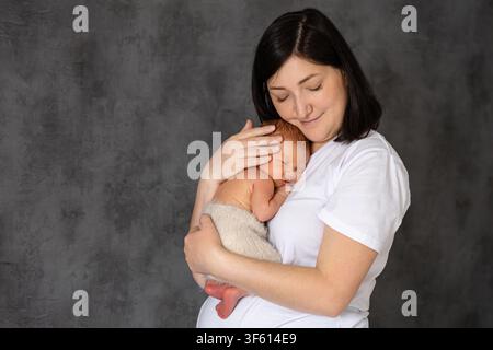 Madre che abbraccia il neonato in un momento di amore Foto Stock