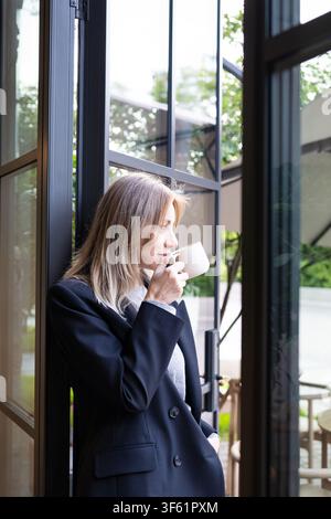 Una donna d'affari premurosa e di successo che beve un caffè e si gode una pausa durante la giornata lavorativa. Foto Stock