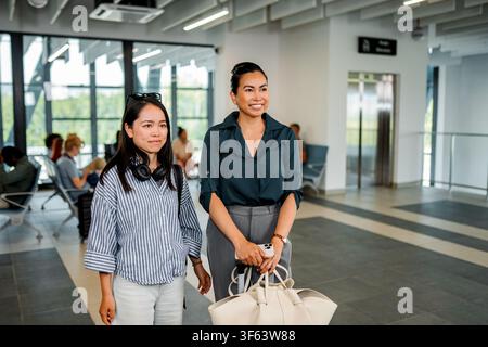 Due donne in viaggio, che camminano attraverso il terminal dell'aeroporto Foto Stock