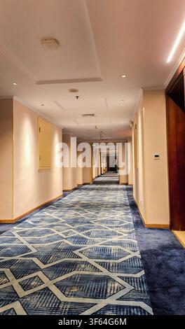 Corridoio lungo e vuoto di un hotel moderno con tappeto a motivi blu Foto Stock