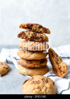 Pile di biscotti fatti in casa con gocce di cioccolato e un biscotto rotto che mostra la consistenza Foto Stock