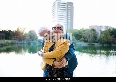 Coppia di anziani affettuosi che si abbracciano e si baciano accanto al lago Foto Stock