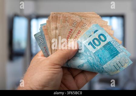Banconote in real brasiliane in mano con messa a fuoco selettiva Foto Stock