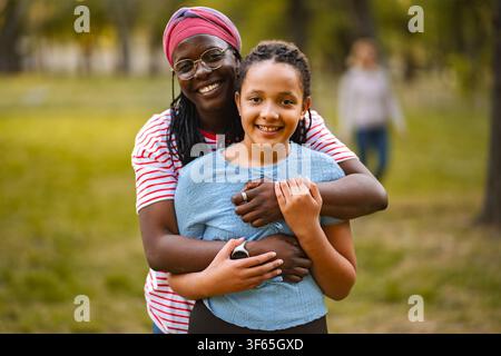 Madre felice che abbraccia una figlia diversificata nel parco Foto Stock