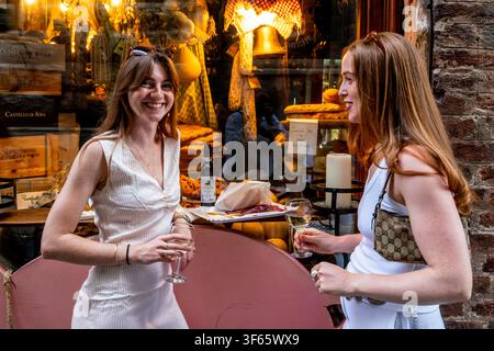 Due turiste britanniche si godono un bicchiere di vino e un piatto di cucina locale fuori da una gastronomia, Siena, Toscana, Italia. Foto Stock