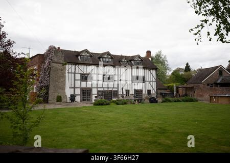Vista posteriore di una grande casa storica in legno a graticcio bianco e nero in stile Tudor con un ampio giardino erboso a Weobley, Herefordshire. Foto Stock