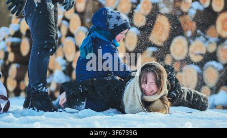 Famiglia felice che gioca nella neve in una bella giornata invernale, godendosi del tempo di qualità insieme Foto Stock