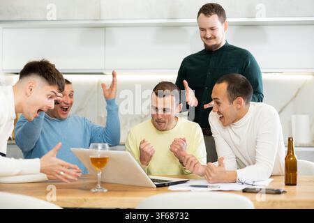 Gruppo di amici che guardano la partita di calcio su un portatile insieme e bevono birra Foto Stock