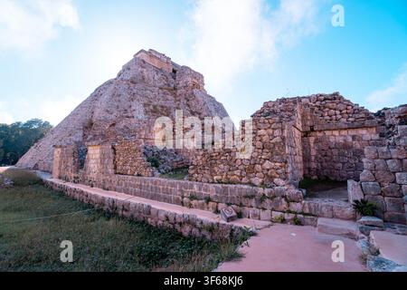 Antica piramide di pietra si erge contro un cielo azzurro terso. Muri erosi incorniciano un sentiero illuminato dal sole che conduce verso l'alto. Gradini salienti invitano all'esplorazione di perdute c Foto Stock