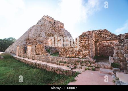 Antica piramide di pietra si erge contro un cielo blu terso. Muri erosi si trovano accanto a terreno erboso e sentiero sterrato. La luce del sole evidenzia la trama del maso invecchiato Foto Stock