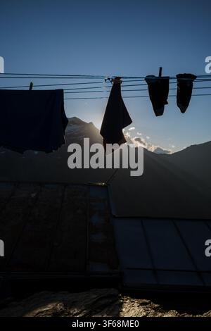 Biancheria che si asciuga su una corda a una capanna di montagna al tramonto, silouettata contro le vette delle Alpi di Hochwurzen, Austria. Foto Stock
