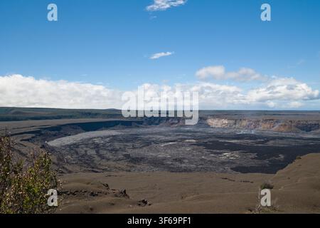 Catturata dall'Uekahuna Overlook nel Parco Nazionale dei Vulcani delle Hawaii, questa veduta mostra la vasta caldera di Kīlauea. Bagnaata dalla luce del giorno Foto Stock