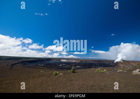 Scattata dall'Uekahuna Overlook all'interno del Parco Nazionale dei Vulcani delle Hawaii, questa veduta mostra la vasta caldera di Kīlauea sotto un cielo blu brillante Foto Stock