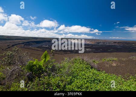 Scattata dall'Uekahuna Overlook, questa veduta mostra la vasta caldera di Kīlauea all'interno del Parco Nazionale dei Vulcani delle Hawaii. Bagna nel chiaro sole diurno Foto Stock