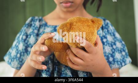 Bambino che tiene un orsacchiotto al chiuso in un ambiente domestico Foto Stock