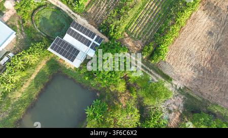 Pannelli solari installati su un edificio di fattoria in campagna con stagni, paesaggio verde e campi agricoli. Energia rinnovabile, sostenibilità ed eco Foto Stock