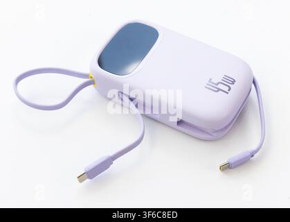 Una power bank moderna viola chiaro con cavi di ricarica integrati è isolata su uno sfondo bianco Foto Stock