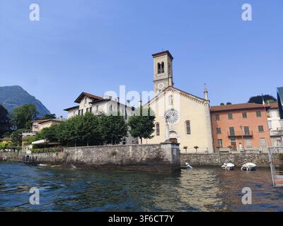 Torre storica della chiesa di Santa Tecla nel villaggio di Torno sulla riva del Lago di Como nella regione lombarda italiana. Torno, Italia - 24 giugno 2026 Foto Stock